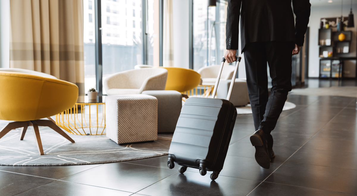 Man wheeling suitcase into hotel lobby